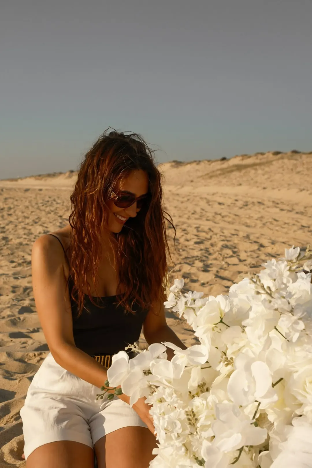 Ana, founder of Picnic Club, among white orchids on the dunes