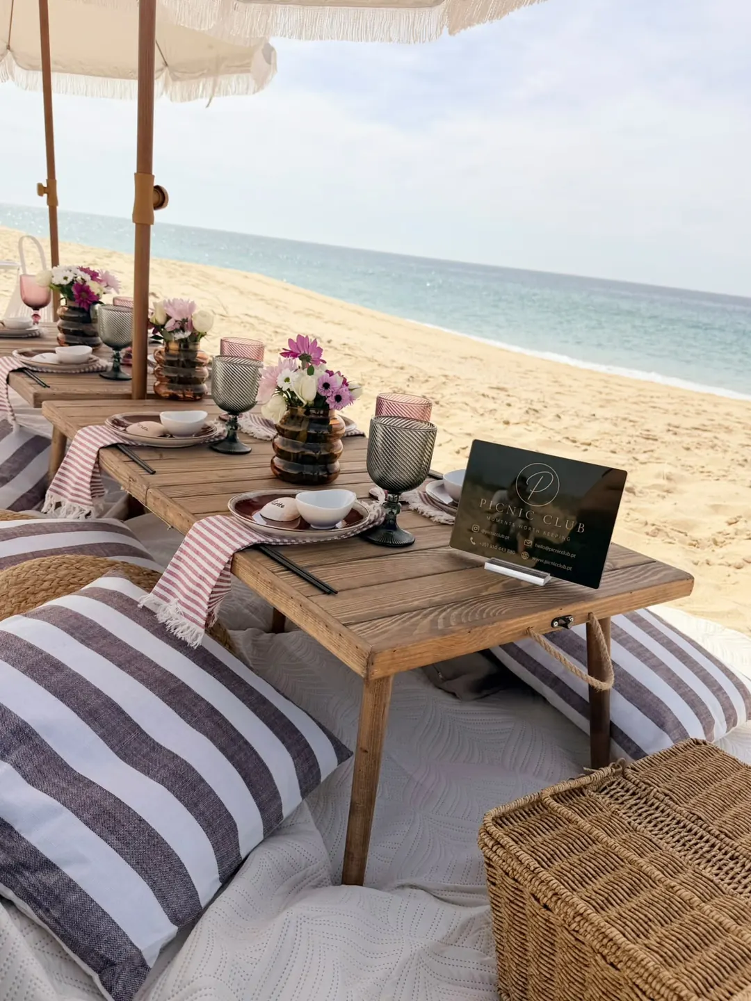 A beach picnic for a private celebration, with striped cushions under a parasol