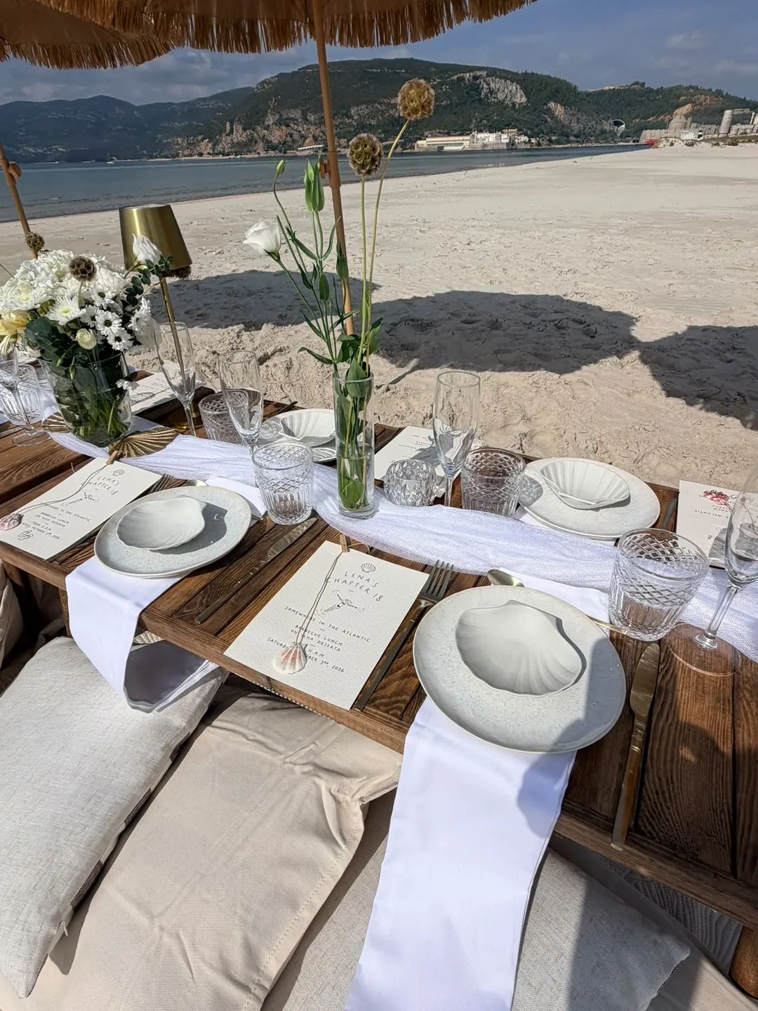 Place settings with shell plates, printed menus and white flowers