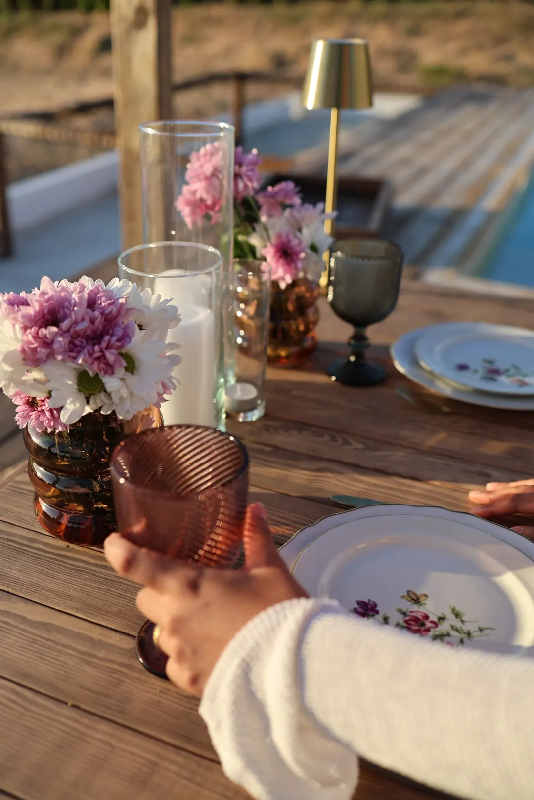 A glass raised at the poolside table