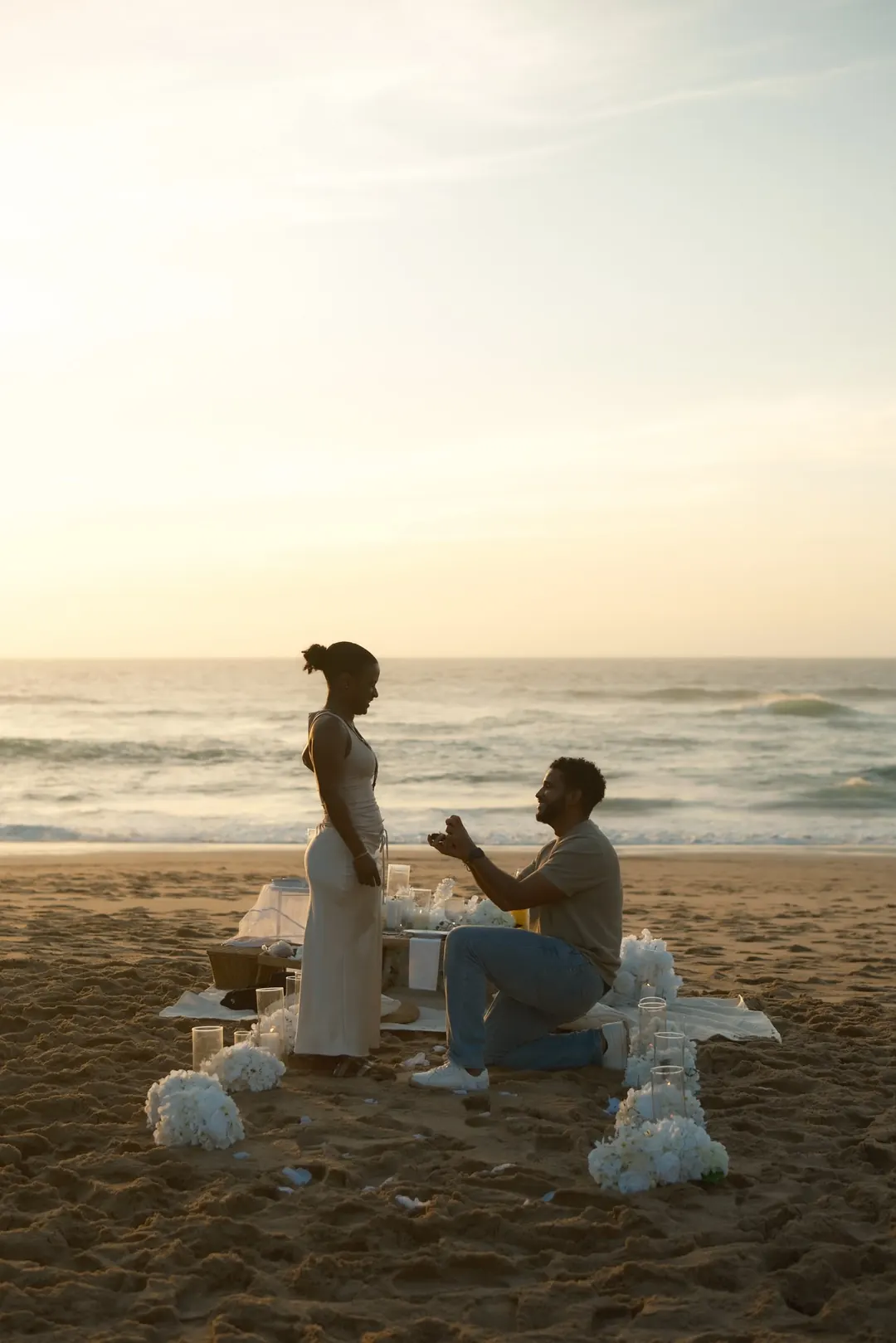 On one knee on the beach, beside the proposal table