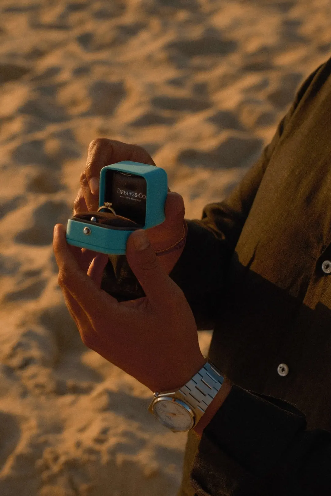 An open ring box held in his hands